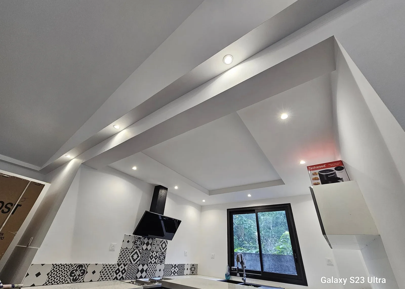 Faux plafond en plâtre avec retombées et spots encastrés au-dessus d'une cuisine